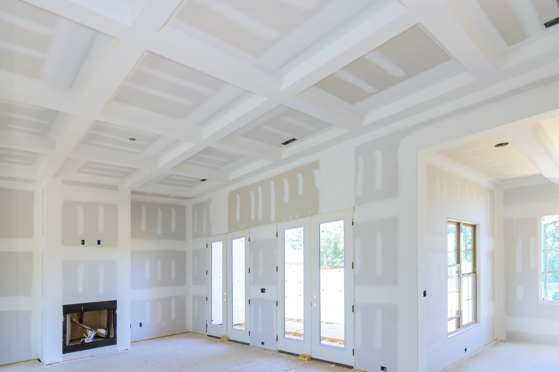 Intérieur de maison en construction avec ouvrier installant des cloisons sèches