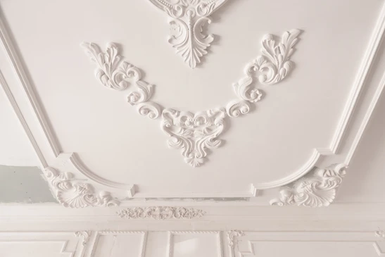 Intérieur résidentiel avec ouvrier installant une moulure décorative blanche au-dessus d'un encadrement de porte
